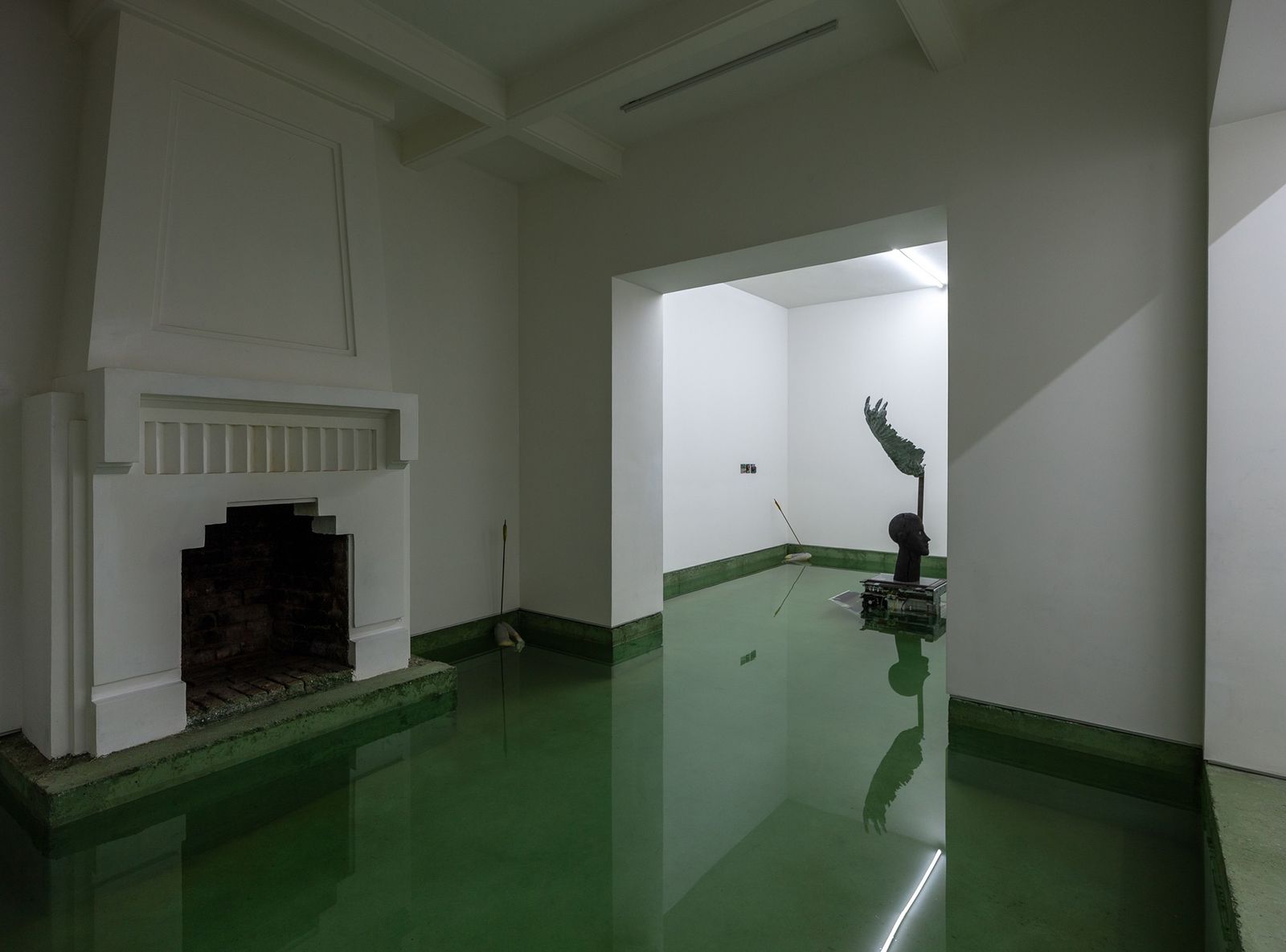 Sala inundada con chimenea; en la sala siguiente, una escultura de cabeza y ala