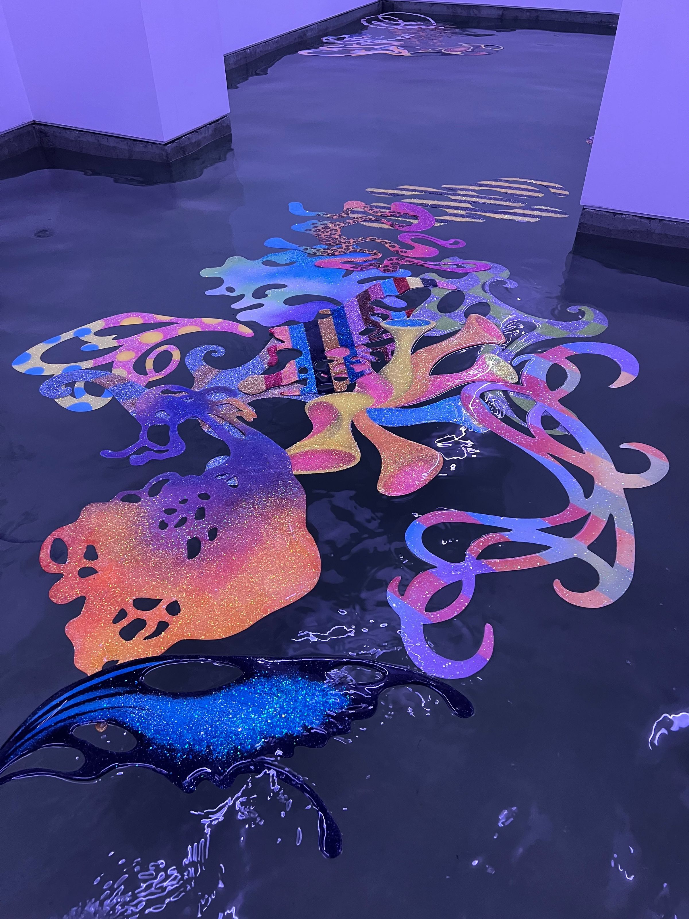 Piezas de resina con glitter de colores flotando en la sala inundada, un vano al fondo
