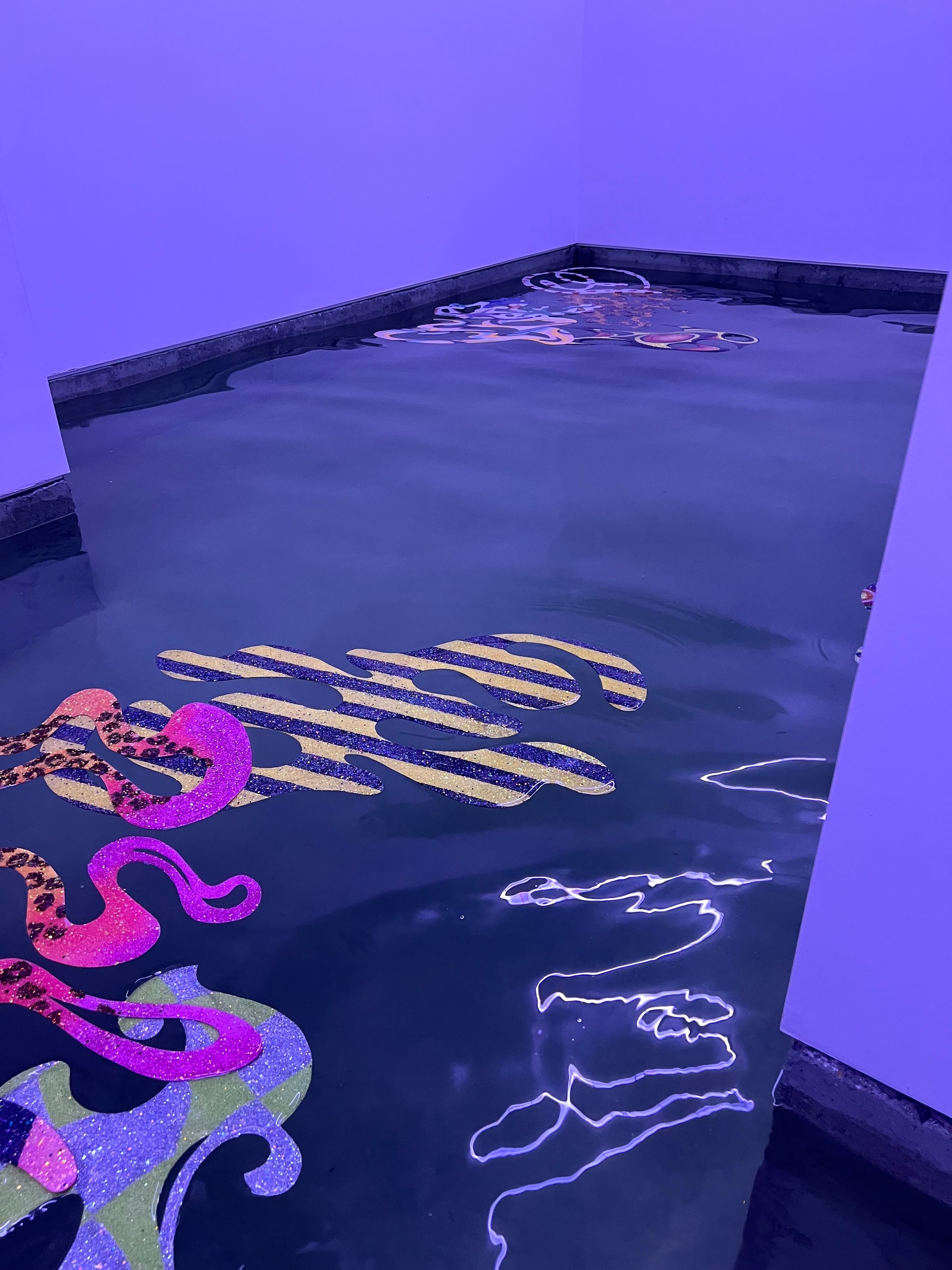Pieza de rayas amarillas y violetas junto a formas rosadas, reflejos de luz en el agua