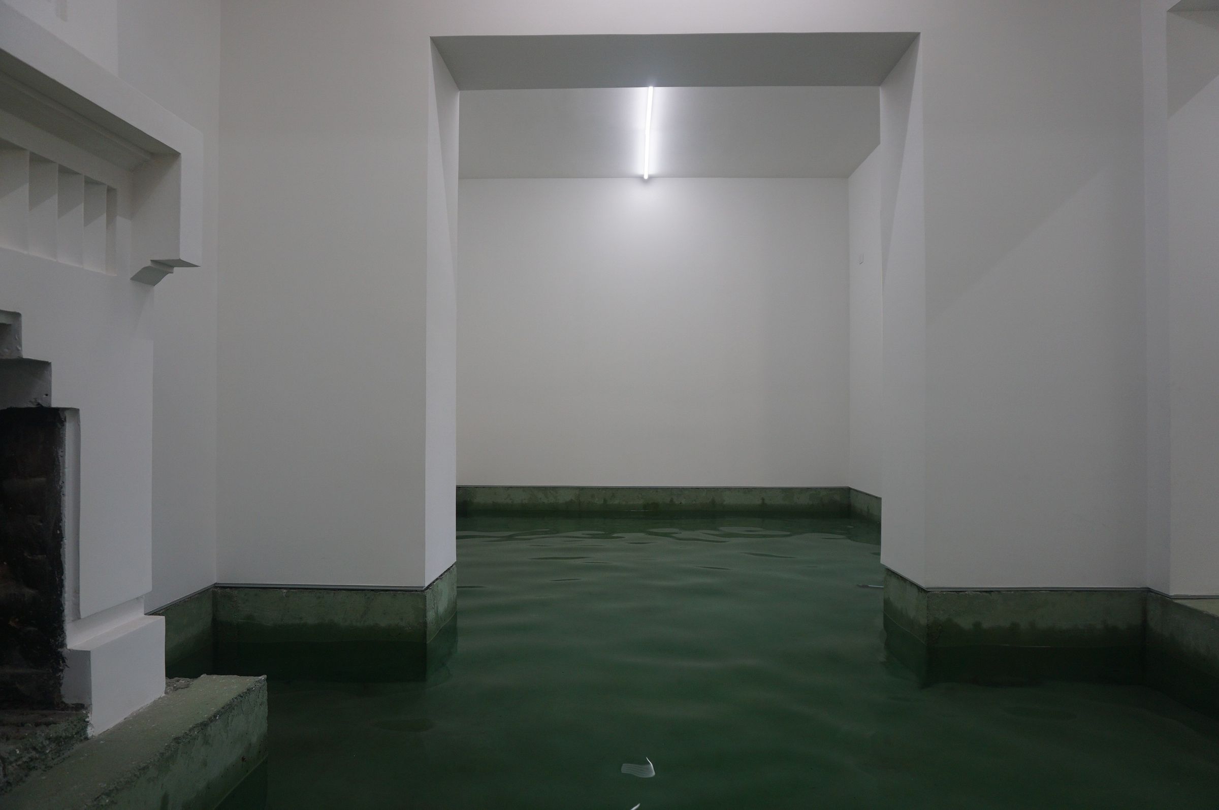 A través de un vano hacia la sala inundada, chimenea a la izquierda. Arquitectura: Smiljan Radic
